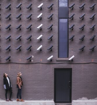 two women facing security camera above mounted on structure